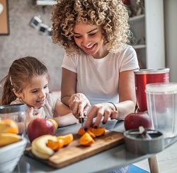 Lady cutting fruit with her daughter in her kitchen